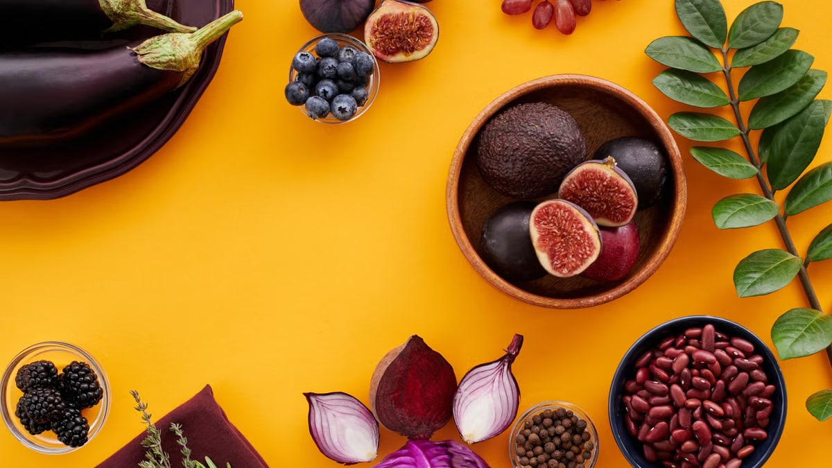 Colorful assortment of fruits, vegetables, and herbs on a vibrant yellow background in a flat lay style.